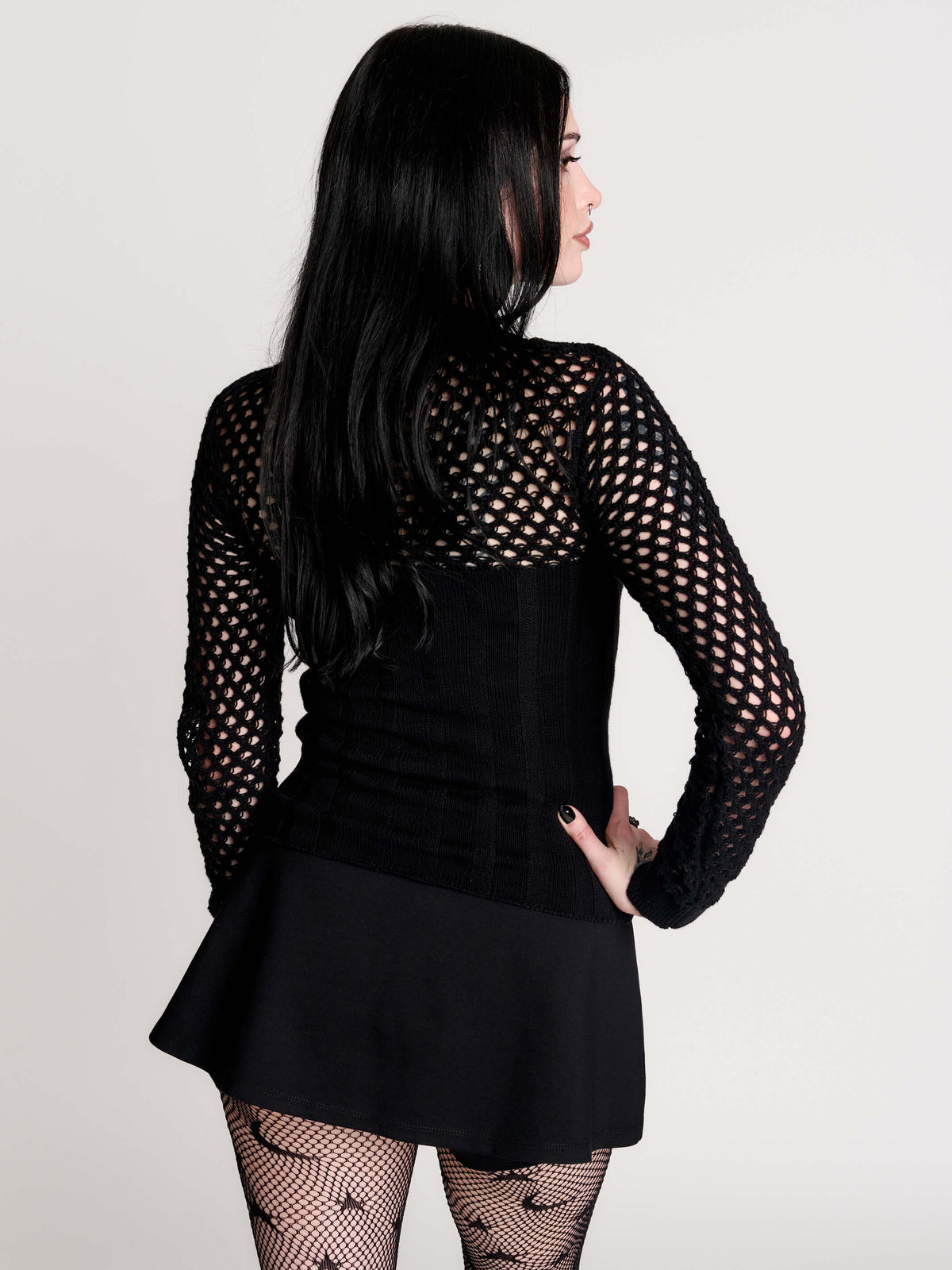 Fishnet Sweetheart Rib Sweater, a black long-sleeve top with a fitted rib-knit body and fishnet across the upper chest, shoulders, upper back and sleeves, giving a “sweetheart” illusion while keeping the sleek silhouette sleek.