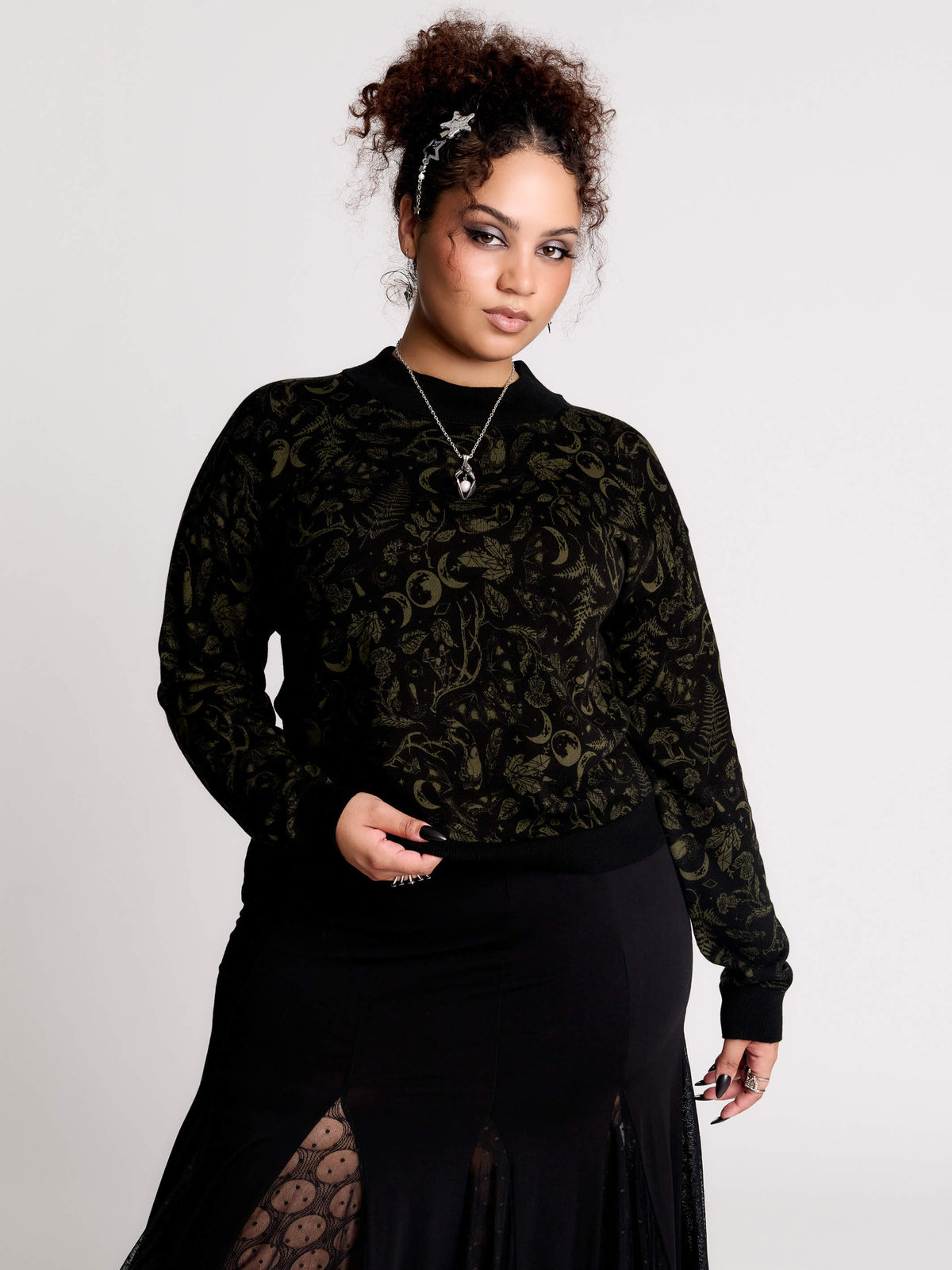 a black long-sleeve top with an intricate olive green forest findings pattern
