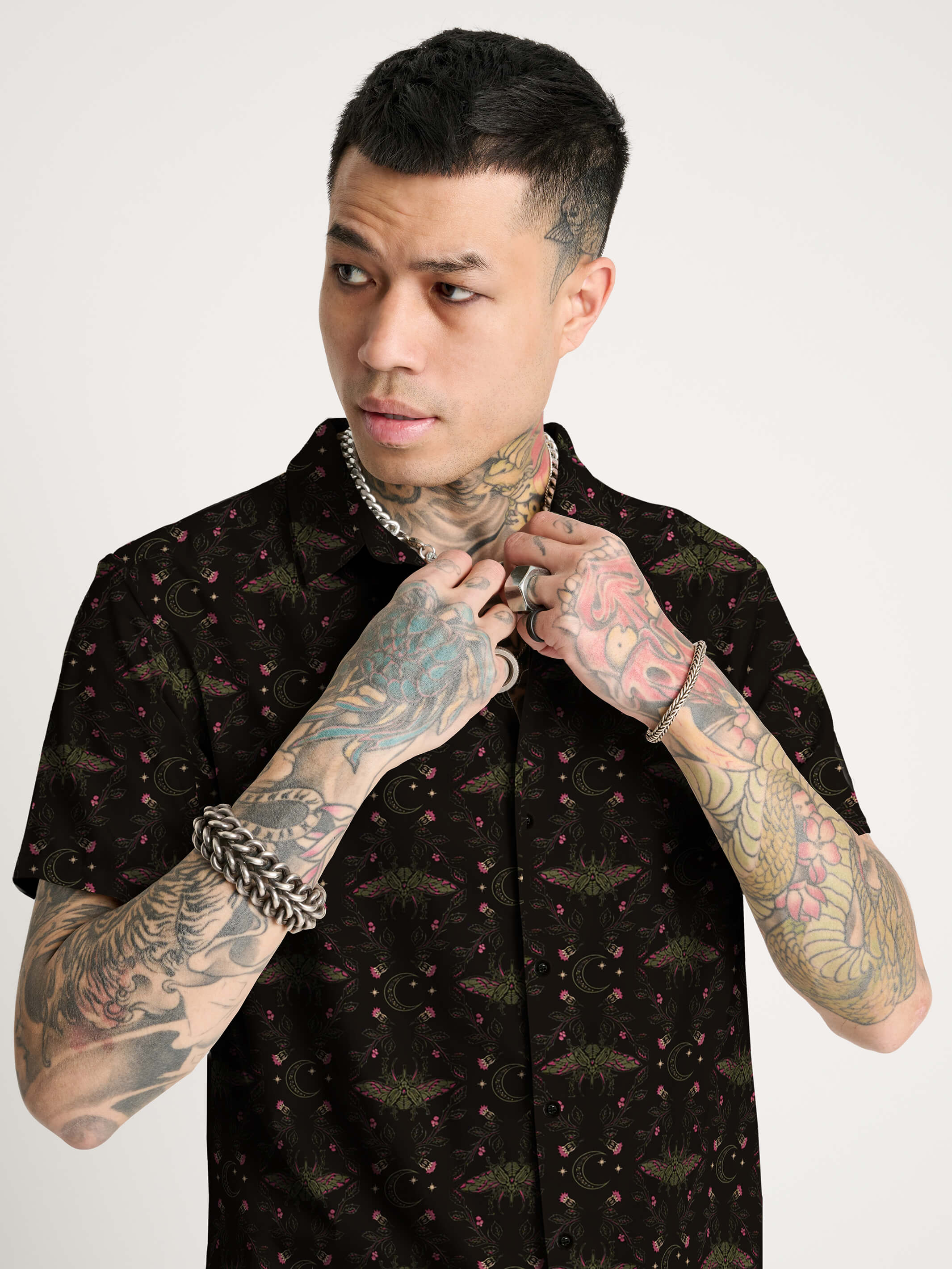 A black short-sleeve button-up shirt with repeating red and green scarab beetle pattern.