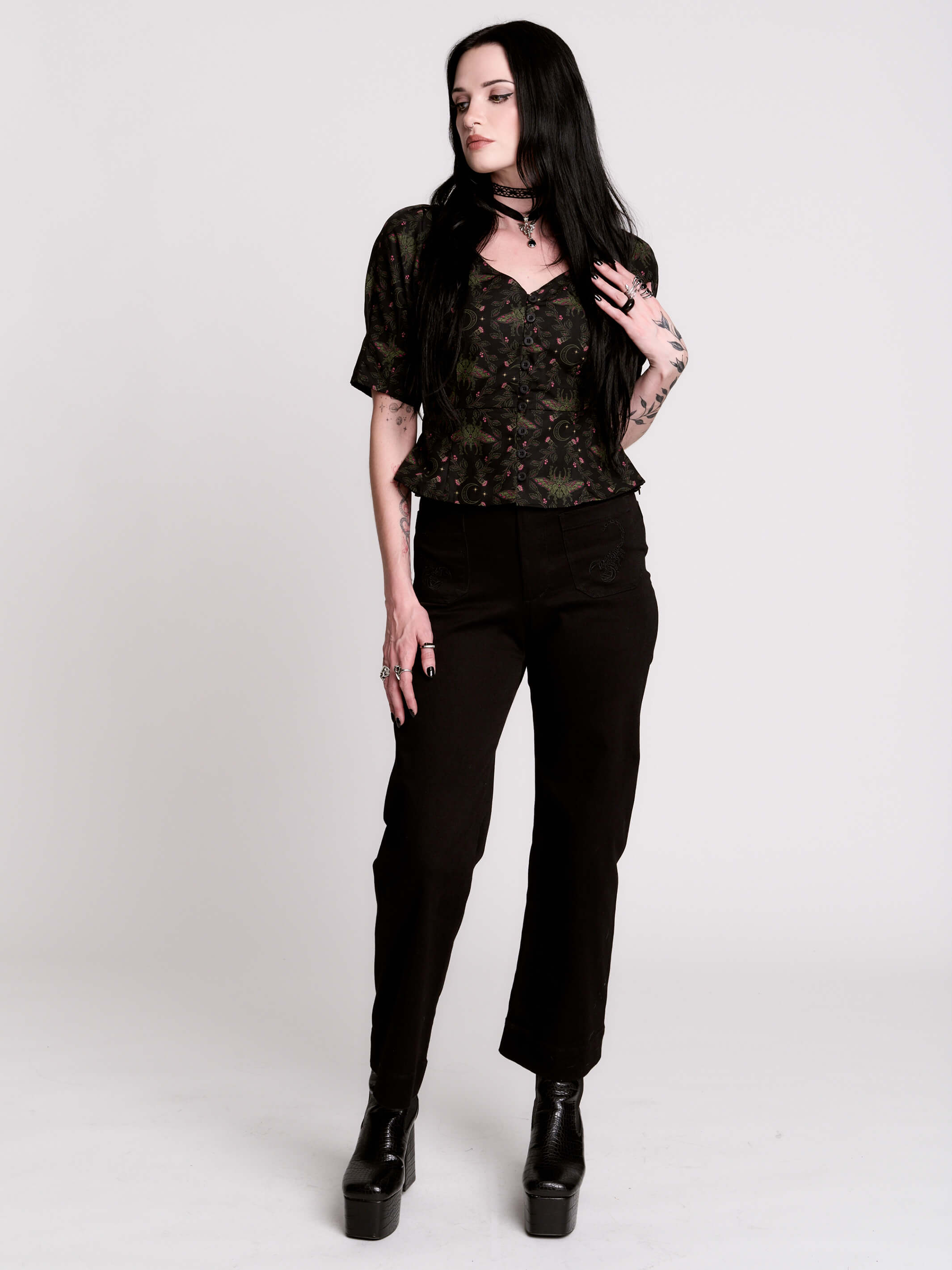 A short-sleeve button-up blouse featuring a dark green and black gothic pattern with pink accents.
