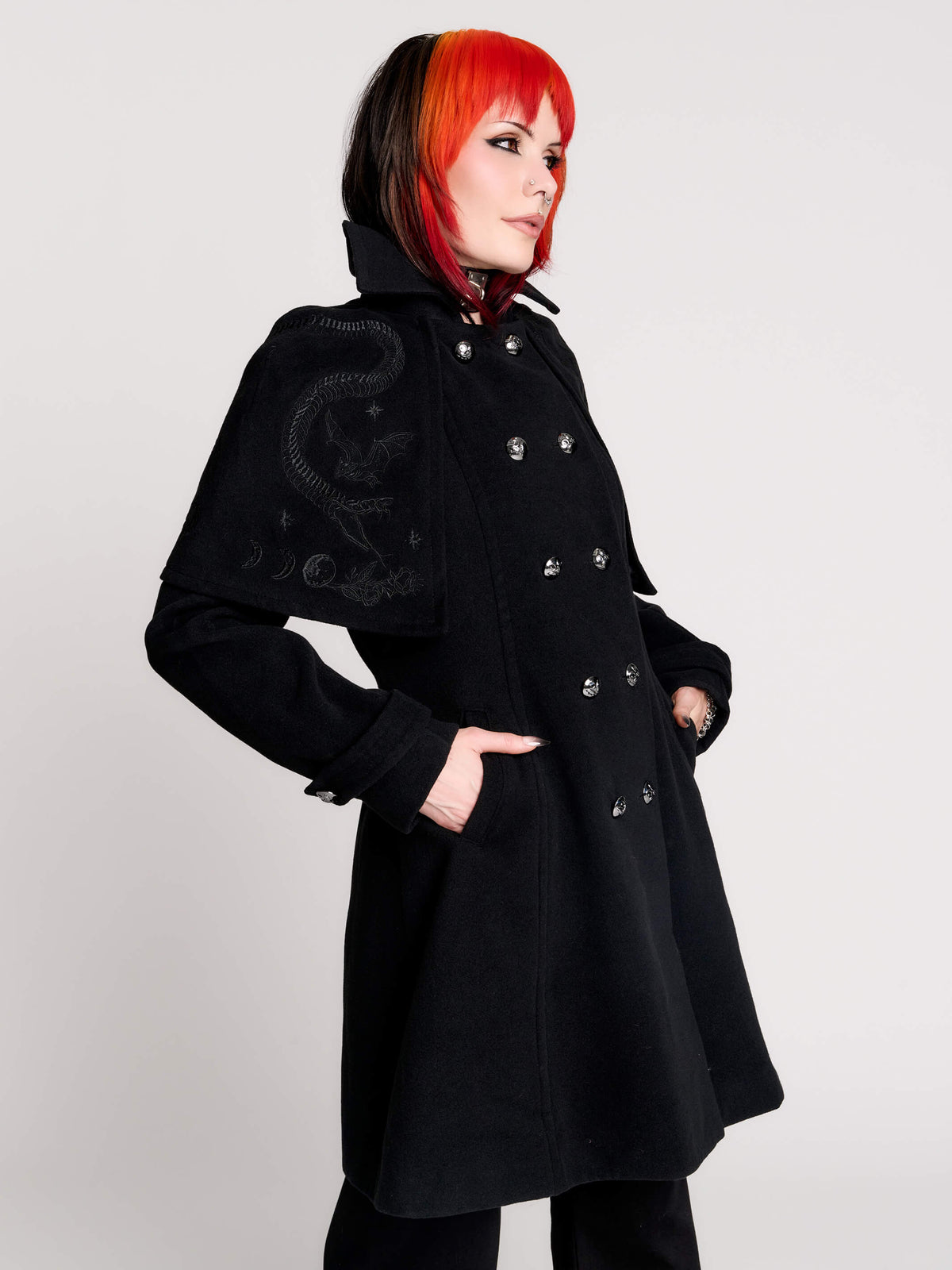 a black double-breasted coat with silver buttons and gothic dragon embroidery on the shoulder cape