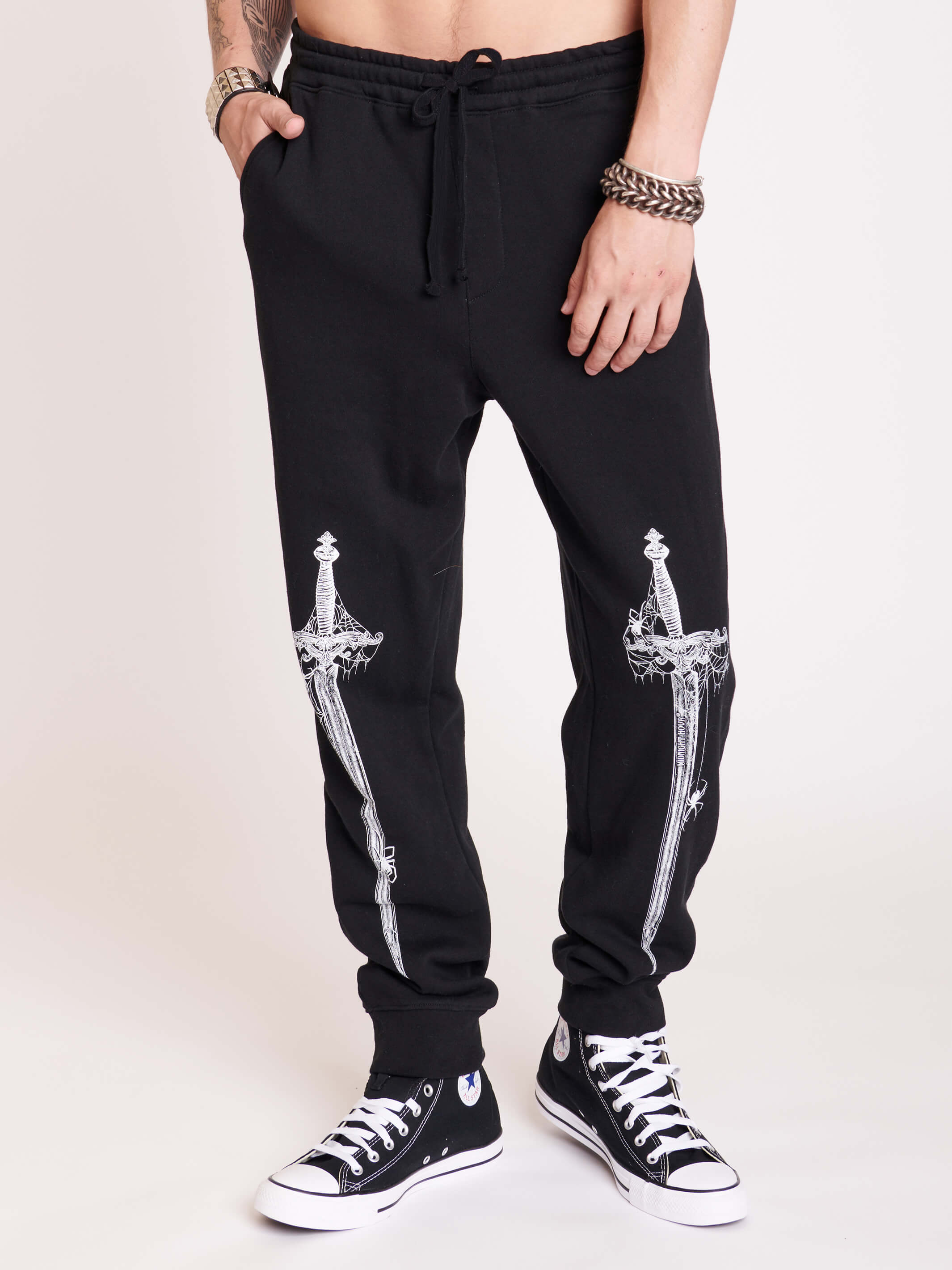 Black joggers with white dagger graphic from thighs to shins