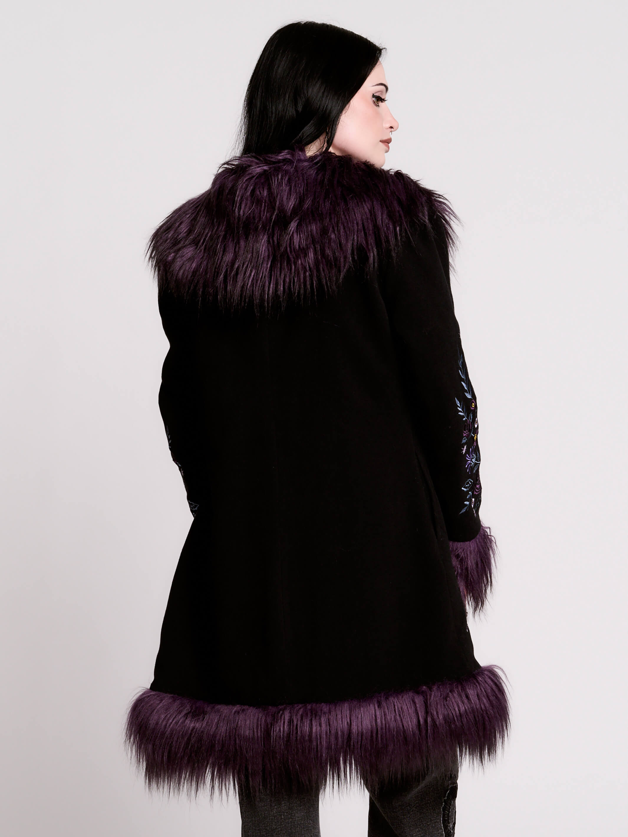 This mid-length black coat pairs a soft, suede-like finish with plush amethyst-purple faux fur trim