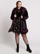 This mid-length black coat pairs a soft, suede-like finish with plush amethyst-purple faux fur trim