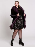 This mid-length black coat pairs a soft, suede-like finish with plush amethyst-purple faux fur trim