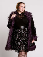 This mid-length black coat pairs a soft, suede-like finish with plush amethyst-purple faux fur trim