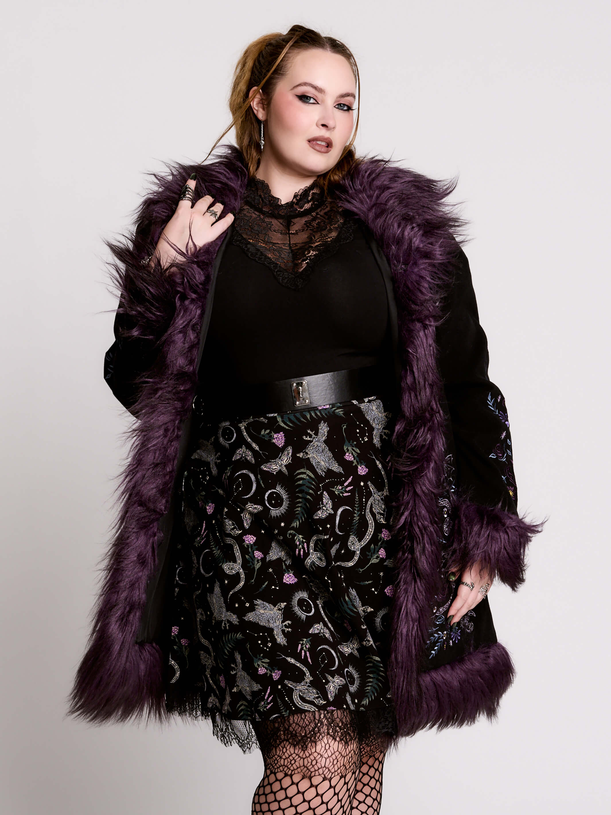 This mid-length black coat pairs a soft, suede-like finish with plush amethyst-purple faux fur trim