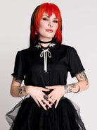 black short-sleeve blouse with white embroidered bat on collar and black lace trim