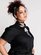 black short-sleeve blouse with white embroidered bat on collar and black lace trim