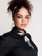 black short-sleeve blouse with white embroidered bat on collar and black lace trim