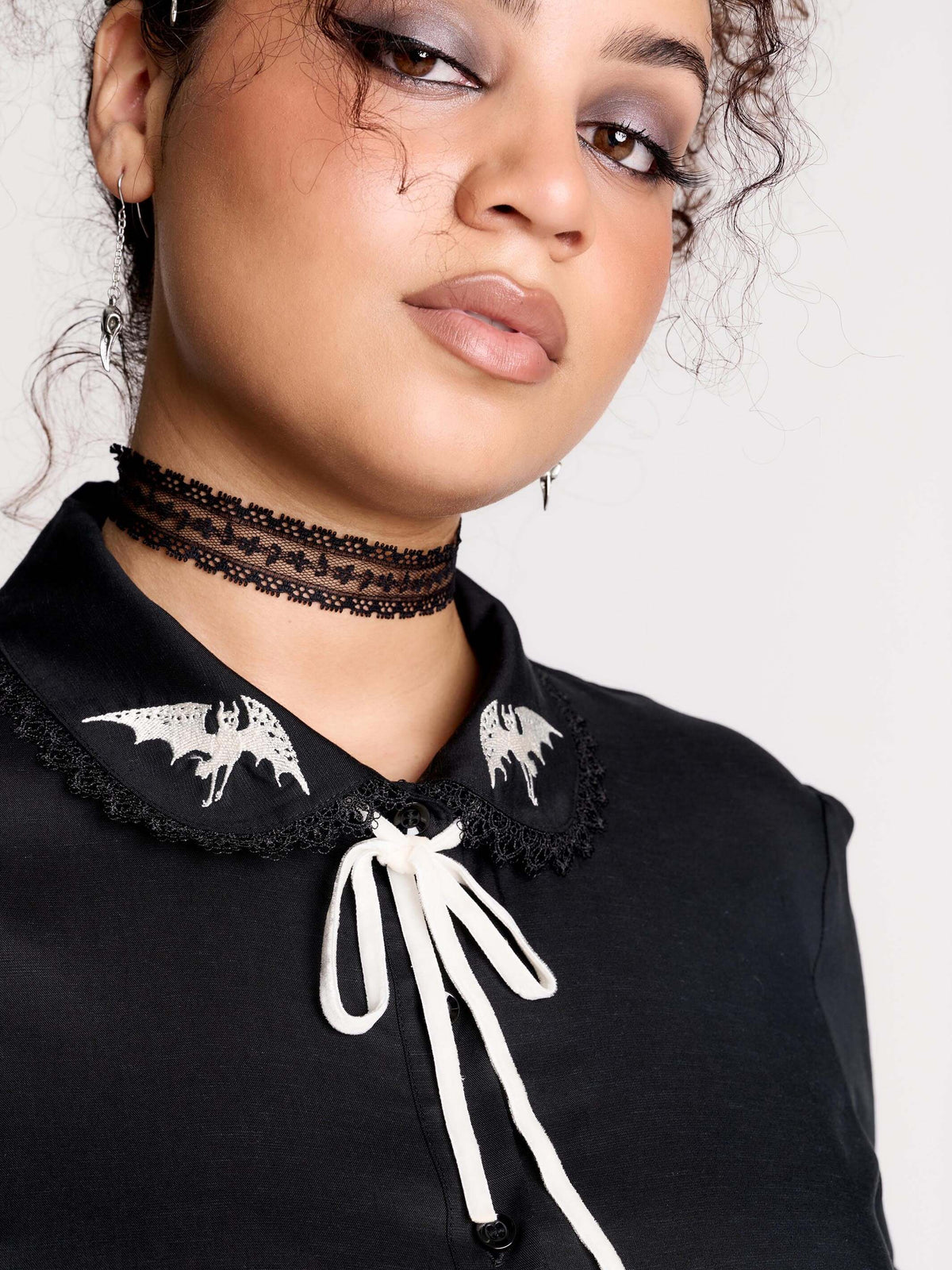 black short-sleeve blouse with white embroidered bat on collar and black lace trim