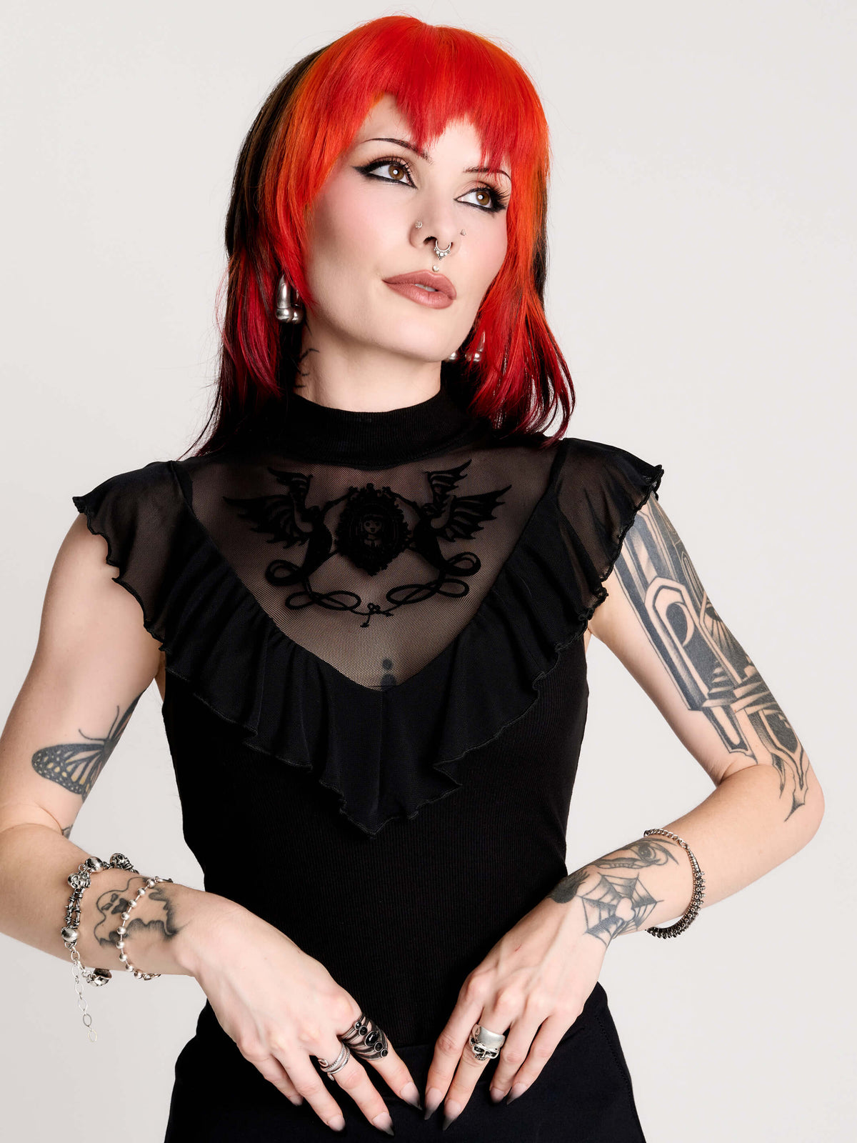 a black sheer mock-neck top with a black graphic on the chest