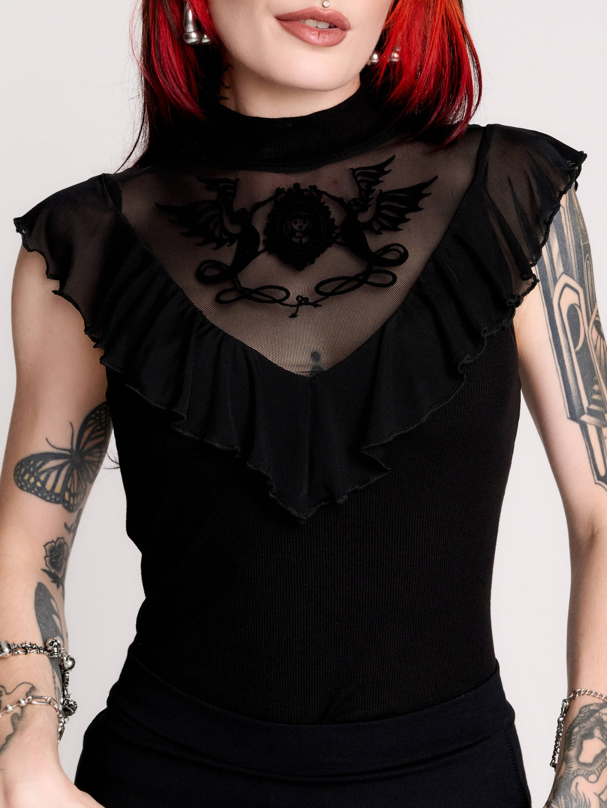 a black sheer mock-neck top with a black graphic on the chest