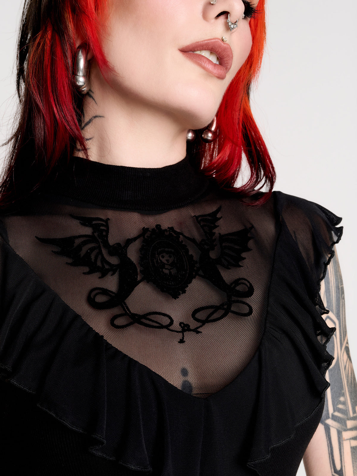 a black sheer mock-neck top with a black graphic on the chest