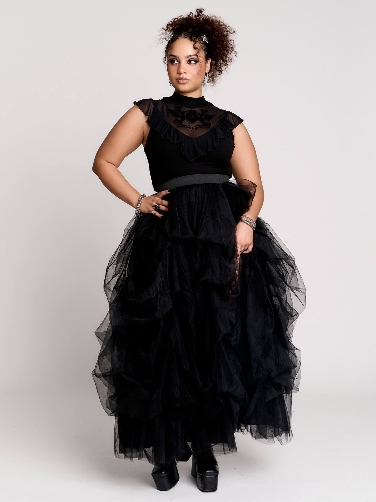a black sheer mock-neck top with a black graphic on the chest