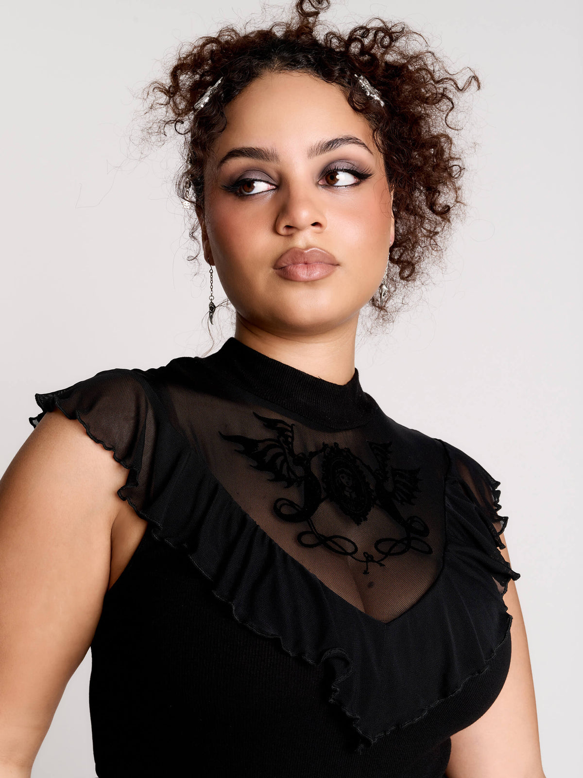 a black sheer mock-neck top with a black graphic on the chest
