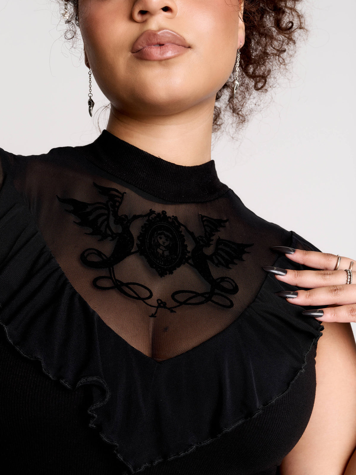 a black sheer mock-neck top with a black graphic on the chest