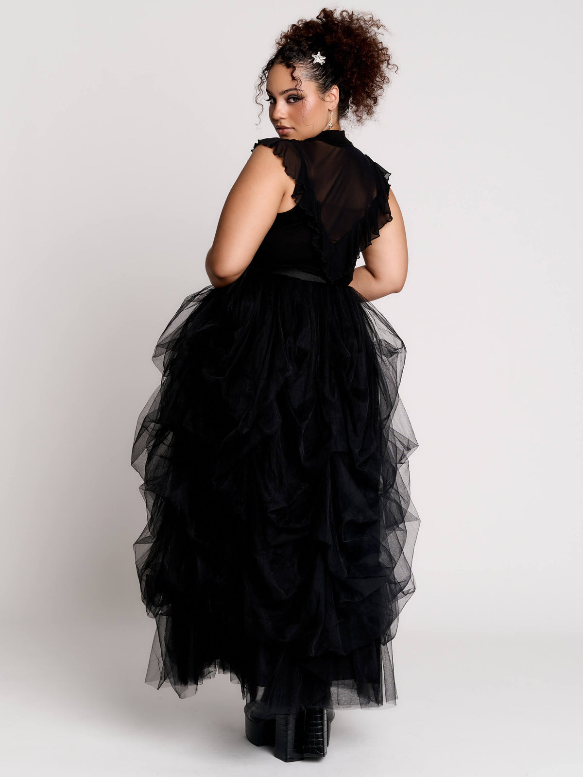a black sheer mock-neck top with a black graphic on the chest