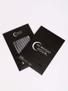 Two black Midnight Hour product boxes on a clean white background, with one box showing a clear window revealing a textured item inside.