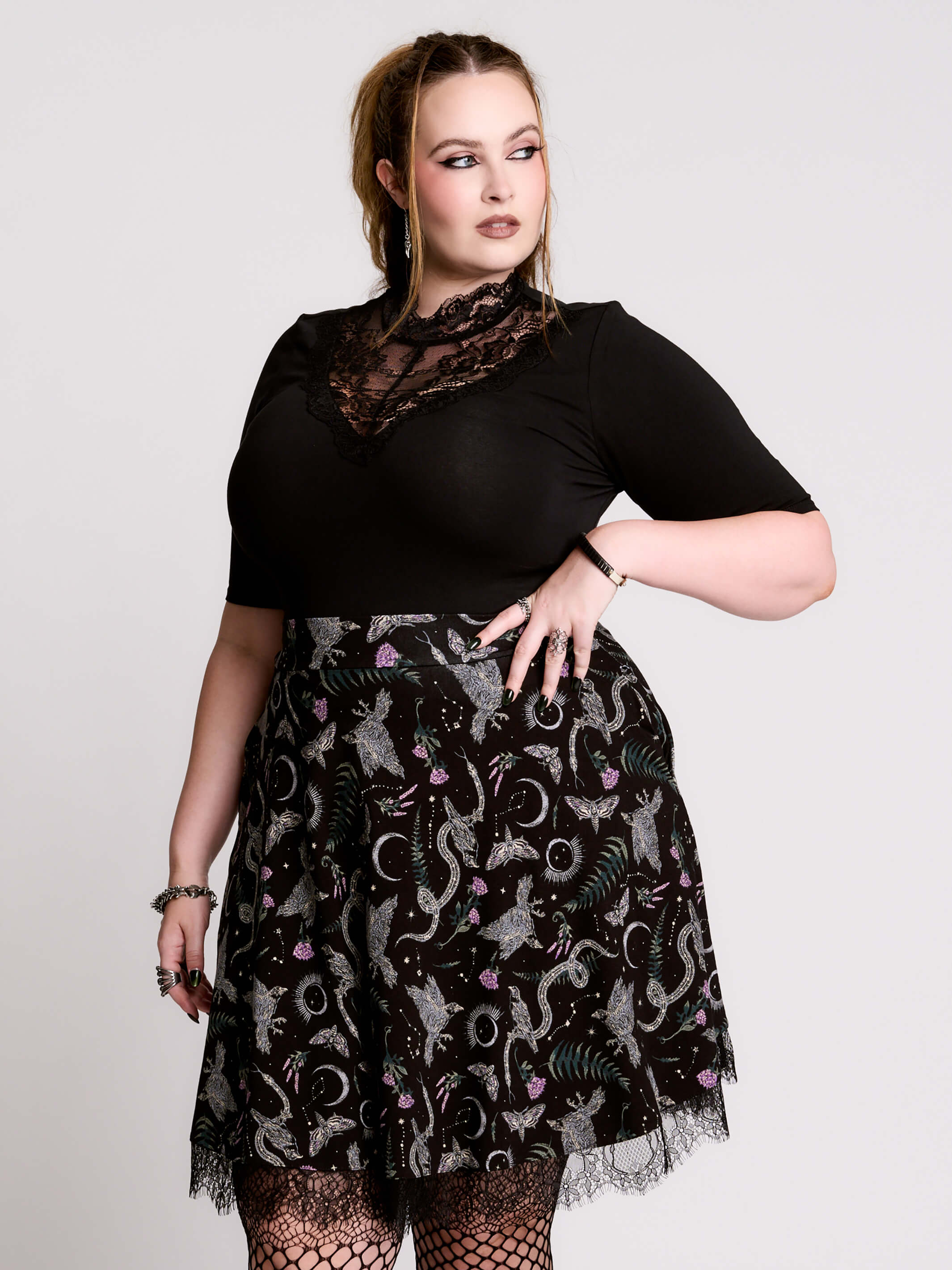 A  black flared skirt featuring a gray and purple gothic print with lace hem.