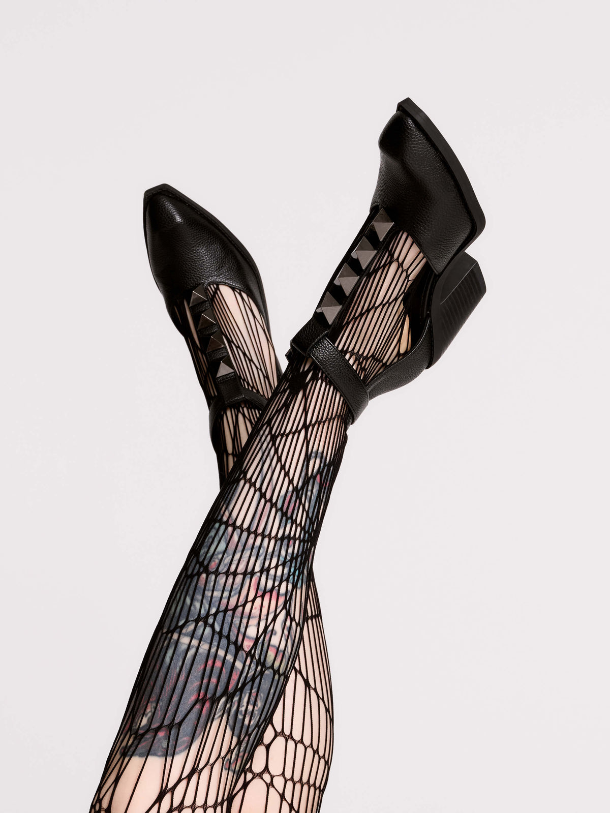 A pair of black leather ankle-strap block-heel shoes with pointed toes and silver pyramid stud embellishments.