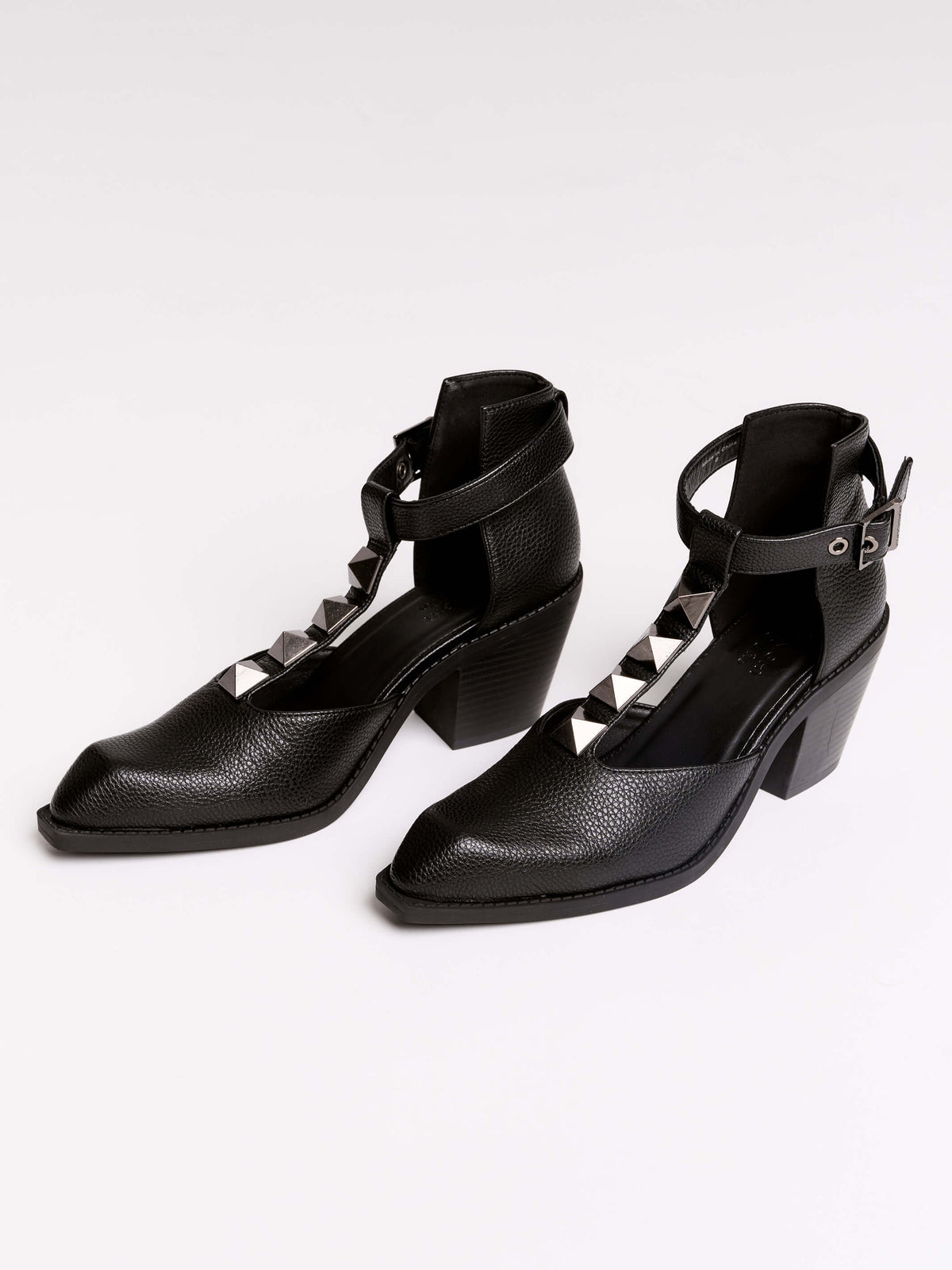 A pair of black leather ankle-strap block-heel shoes with pointed toes and silver pyramid stud embellishments.