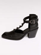 A pair of black leather ankle-strap block-heel shoes with pointed toes and silver pyramid stud embellishments.