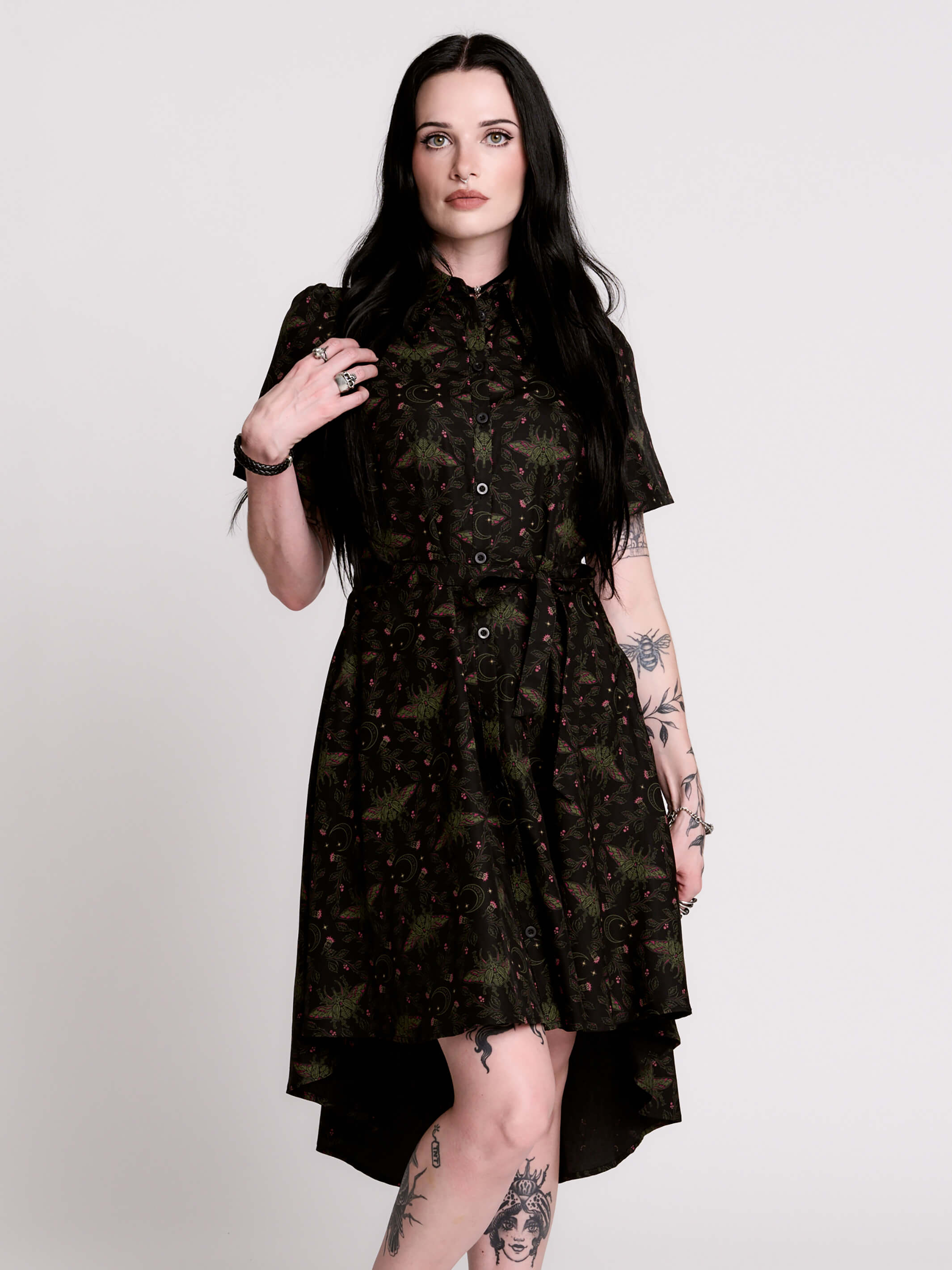 a short-sleeved high-low dress in black with a small red and green floral pattern.
