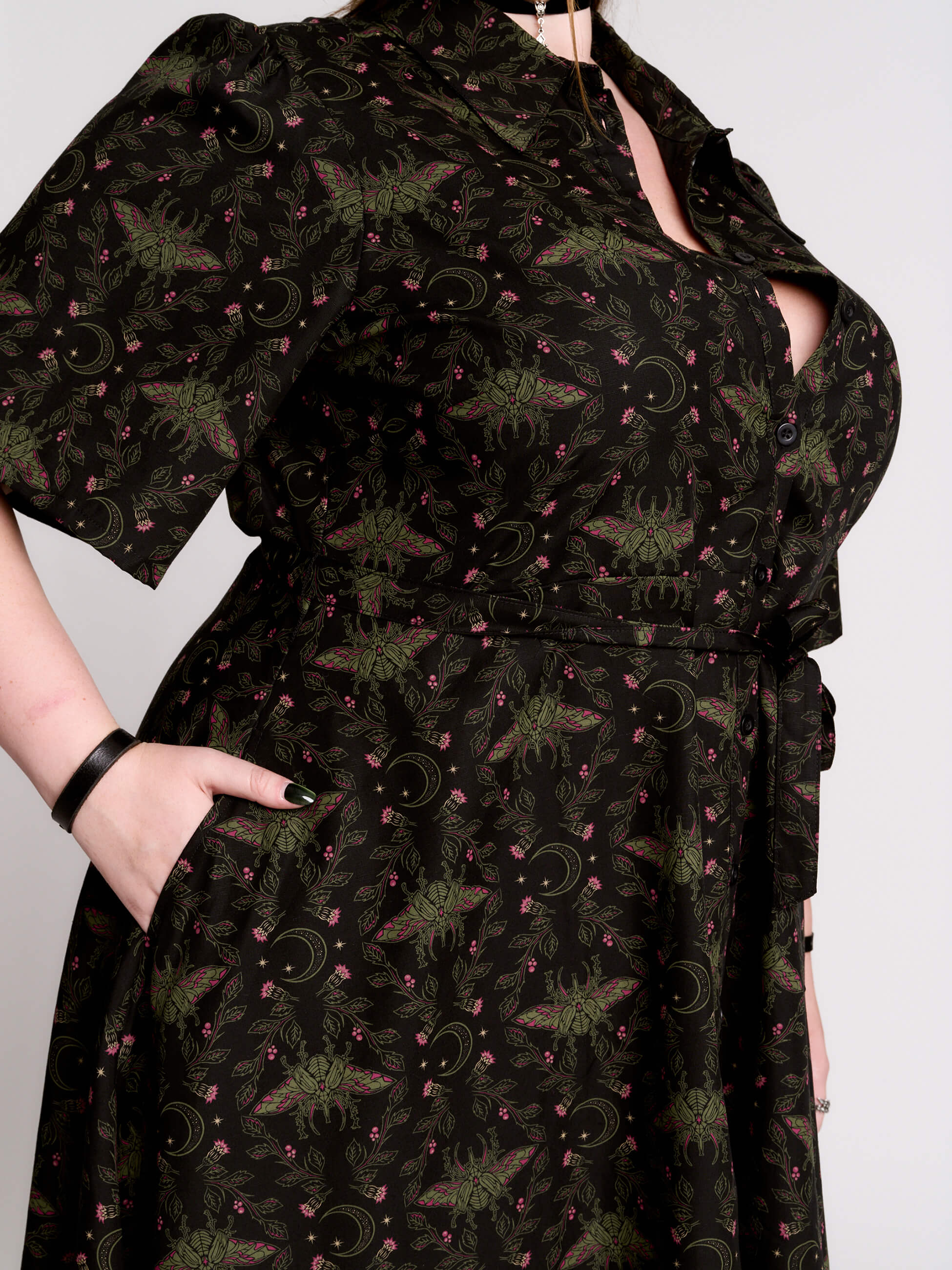 a short-sleeved high-low dress in black with a small red and green floral pattern.