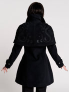 a black double-breasted coat with silver buttons and gothic dragon embroidery on the shoulder cape