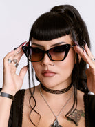 Woman wearing cat-eye sunglasses with a neutral background