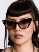Woman wearing black cat-eye sunglasses with a neutral background