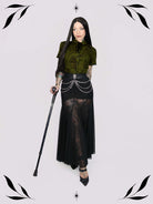 a short-sleeve olive green blouse with a dark botanical pattern, black lace trim collar with black ribbon tiedetail and black buttons. 