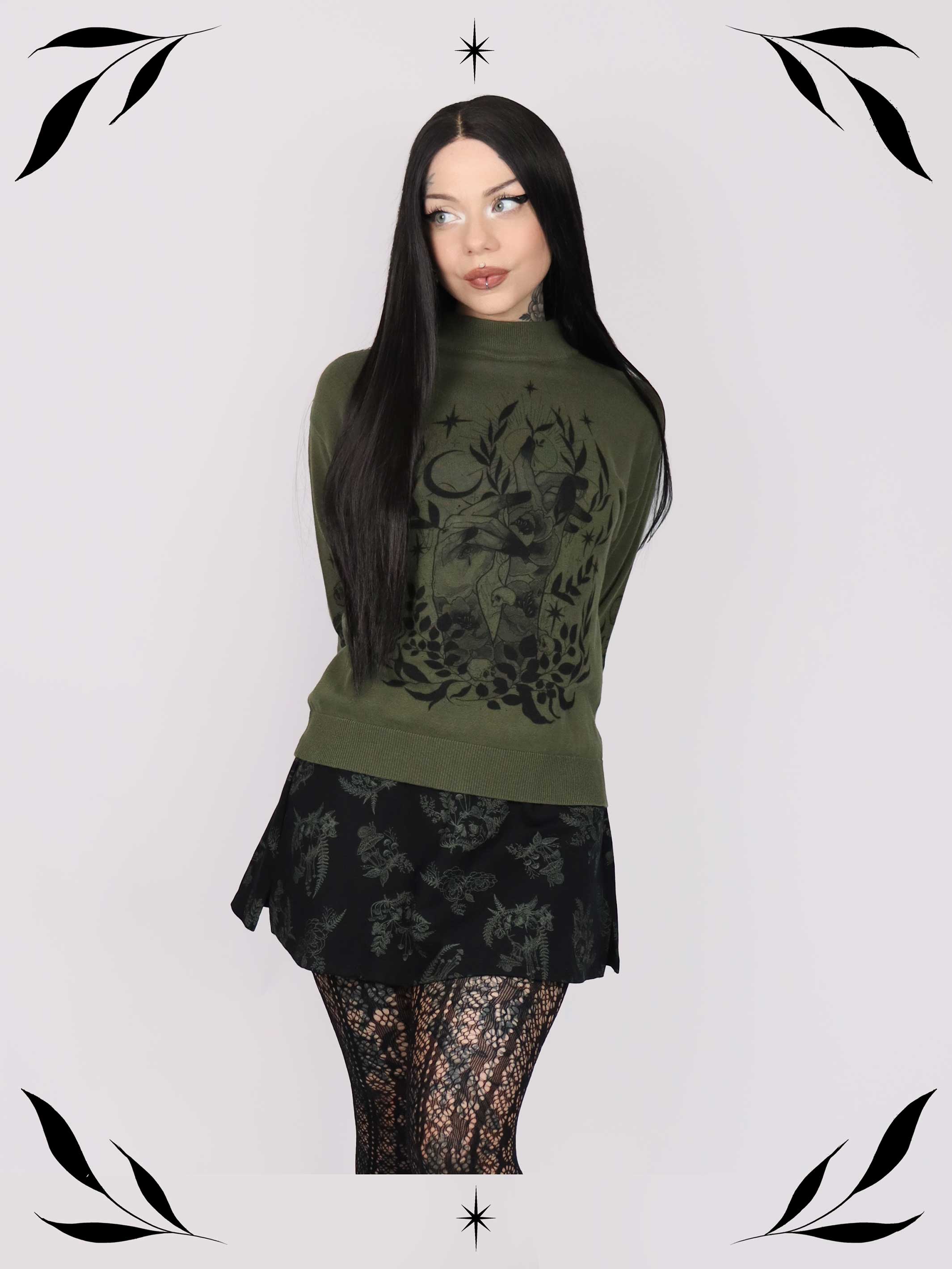 an olive green mock-neck sweater featuring a black gothic graphic