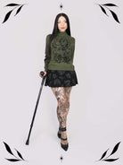an olive green mock-neck sweater featuring a black gothic graphic