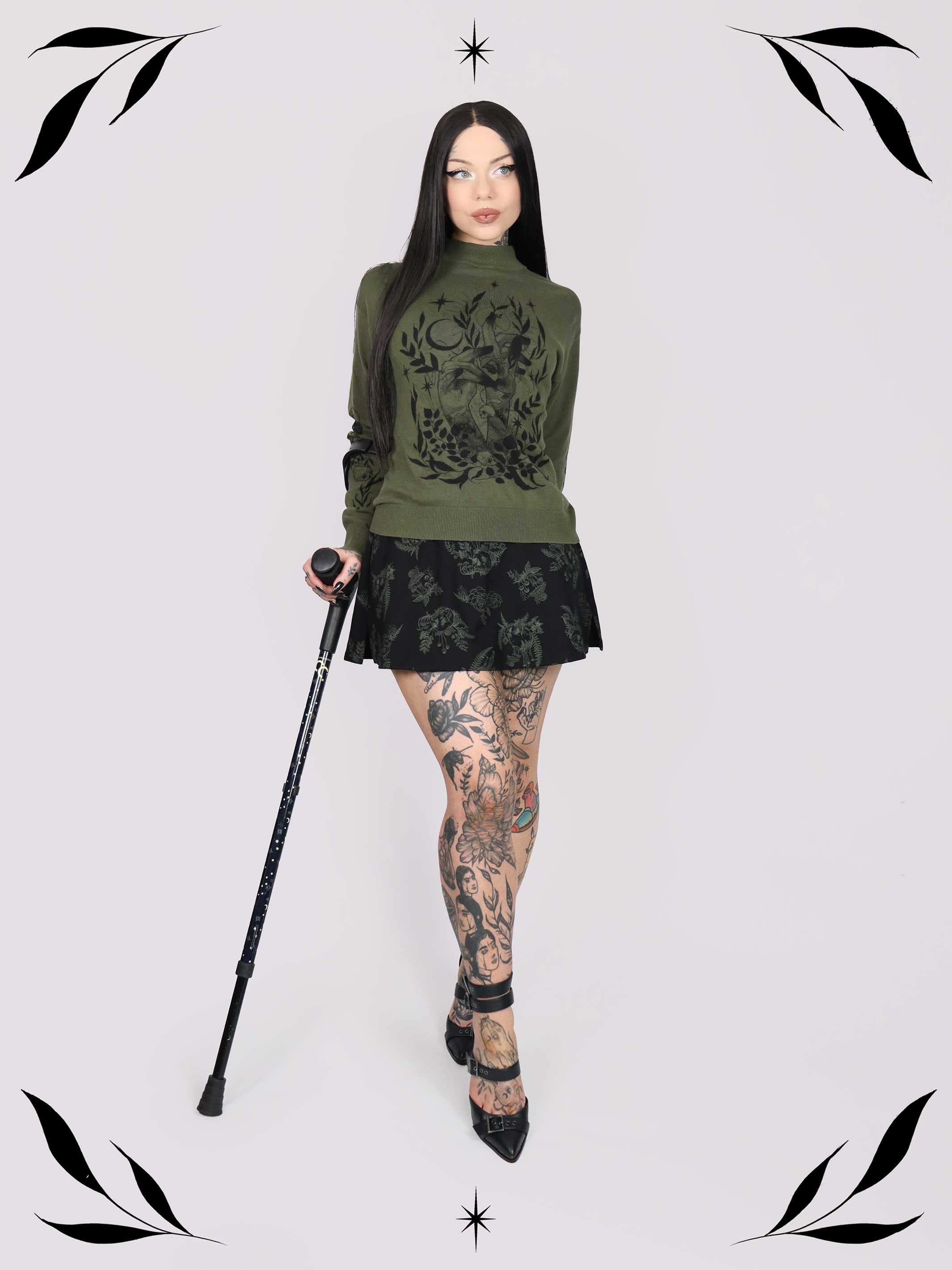 an olive green mock-neck sweater featuring a black gothic graphic