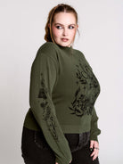 an olive green mock-neck sweater featuring a black gothic graphic