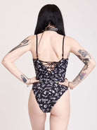 black one piece swim suit with a white all over print and lace up detail front and back middle